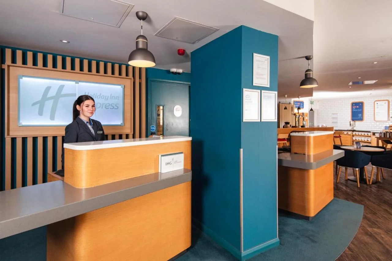 a woman standing at a counter in a waiting room at Holiday Inn Express Bristol City Centre by IHG in Bristol